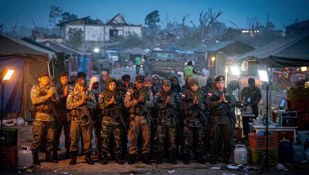 Petugas relawan melaksanakan shalat khauf singkat sambil tetap waspada di lokasi bencana