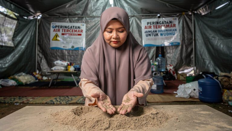 Wanita muslimah mempraktikkan tayamum dengan tanah bersih saat air tercemar pasca bencana